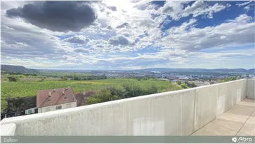 Geräumiger Balkon mit weitem Blick über die Landschaft und die Stadt unter einem bewölkten Himmel.