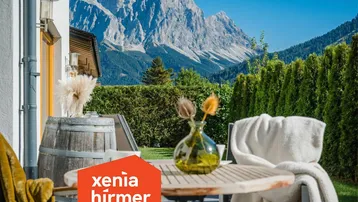 Gemütliche Terrasse mit Holztisch, Stühlen und atemberaubendem Bergblick.