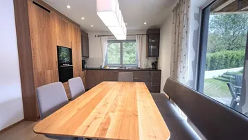 Moderne Wohnküche mit Esstisch, bequemer Sitzbank und Holzelementen, ideal für gemeinsame Mahlzeiten.