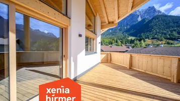 Großer Holzbalkon mit weitem Bergblick und viel Sonnenlicht, ideal zum Entspannen im Freien.