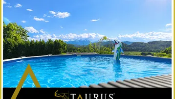Außenbereich mit Pool und Bergblick unter strahlend blauem Himmel.