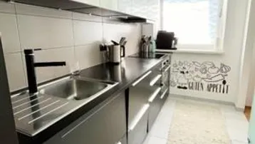 Moderne Küche mit schwarzen Unterschränken, weißen Oberschränken und Fenster.