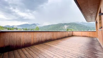 Weitläufige Holzterrasse mit Panoramablick auf die umliegende Berglandschaft.