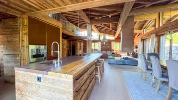Moderne offene Küche mit Holzelementen, Kochinsel, Essbereich und Kamin in einem großzügigen Wohnraum.