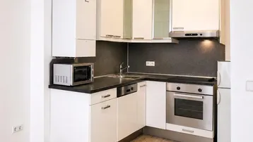 Moderne Einbauküche mit weißen Schränken, dunkler Arbeitsplatte und integrierten Geräten.