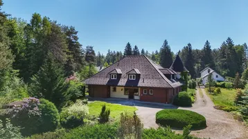 Großzügiges Anwesen mit markantem Dach und weitläufigem Grundstück, umgeben von viel Grün.