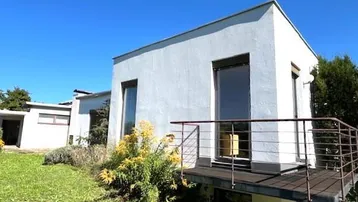 Moderne weiße Fassade des Hauses mit kleinem Balkon und Blick ins Grüne.
