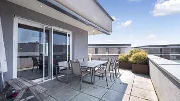 Geräumige Dachterrasse mit Esstisch, Sitzgelegenheiten und Blick auf die Umgebung.