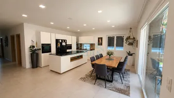 Moderne offene Küche mit Essbereich, Kücheninsel und Zugang zur Terrasse.