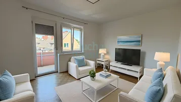 Helles Wohnzimmer mit Parkettboden, bequemen Sofas und Zugang zu einem kleinen Balkon.