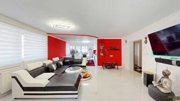 Geräumiges Wohnzimmer mit modernen Fliesen, roten Akzentwänden und einer großen schwarzen Ledercouch.