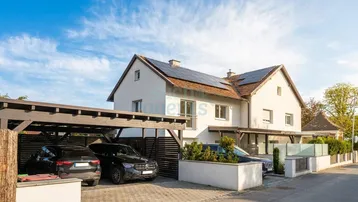 Modernes Einfamilienhaus mit Satteldach, Photovoltaikanlage und Carport für zwei Fahrzeuge.