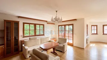 Helles Wohnzimmer mit Holzboden, beigen Möbeln und Zugang zu einem Balkon oder einer Terrasse.