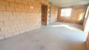 Unfertiger Innenraum mit unverputzten Ziegelwänden und Betonboden, bereit für den Ausbau.