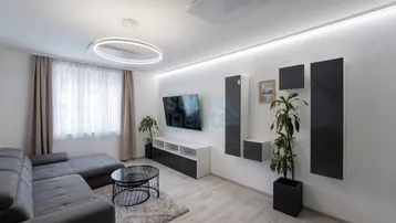 Modernes Wohnzimmer mit bequemer Couch, Fernseher und indirekter Beleuchtung an den Wänden.
