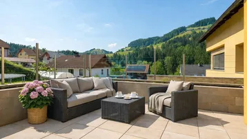 Geräumige Terrasse mit bequemen Outdoor-Möbeln und weitem Blick auf die grüne Hügellandschaft.
