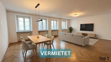 Heller Wohn- und Essbereich mit Fischgrätparkett, modernen Möbeln und großen Fenstern.