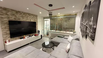 Modernes Wohnzimmer mit großem Ecksofa, Steinwand und Zugang zum Balkon.