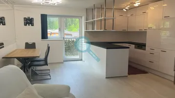 Heller offener Wohn- und Essbereich mit moderner Küche, Holzboden und Zugang zum Balkon.