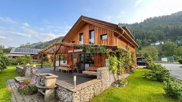 Charmantes Holzhaus mit großer Terrasse, Grillplatz und Bergblick in ländlicher Umgebung.