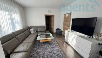 Geräumiges Wohnzimmer mit bequemer Eckcouch, modernem TV-Möbel und Laminatboden.