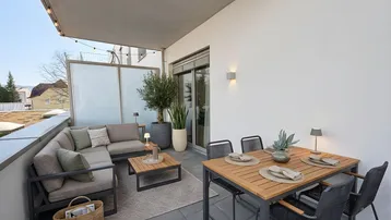 Geräumige Terrasse mit modernen Gartenmöbeln, Essbereich und gemütlicher Lounge-Ecke für entspannte Stunden im Freien.