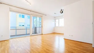 Helles Wohnzimmer mit Parkettboden und Zugang zu einem Balkon, ideal für individuelle Gestaltung.