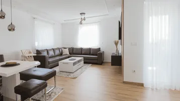 Heller, offener Wohn- und Essbereich mit bequemer Ledercouch und modernem Laminatboden.