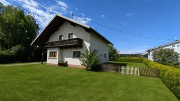 Freistehendes Einfamilienhaus mit Satteldach, Balkon und großem, gepflegten Garten auf sonnigem Grundstück.