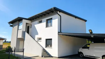 Modernes Einfamilienhaus mit weißer und grauer Fassade, Rollläden und integriertem Carport.