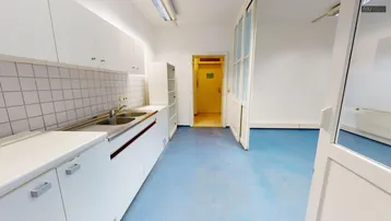 Funktionale Küche mit weißen Einbauschränken, Doppelwaschbecken und blauem Bodenbelag, ideal als Teeküche.