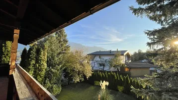 Panoramablick vom Balkon auf die umliegende Berglandschaft und den gepflegten Garten.