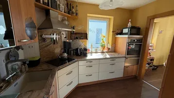 Funktionale Küche mit hellen Fronten, Granitarbeitsplatte und integrierten Geräten.