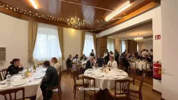 Großer Speisesaal mit Holzboden, festlicher Beleuchtung und vielen Gästen an runden Tischen, ideal für Veranstaltungen.