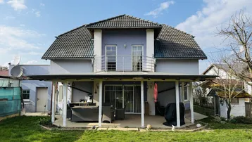Rückansicht des Hauses mit großem Garten und überdachter Terrasse, ideal für Entspannung im Freien.