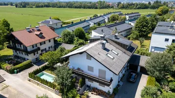 Haus in ländlicher Umgebung mit Bergblick und angrenzenden Feldern.