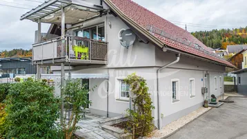 Traditionelles Haus mit rotem Ziegeldach und einem möblierten Balkon mit Überdachung.