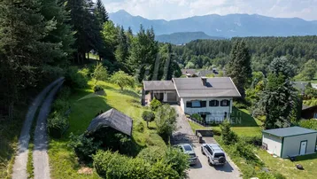 Weitläufige Luftaufnahme des Anwesens mit Zufahrt, umgeben von Natur und Bergblick im Hintergrund.