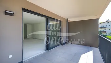 Geräumiger Balkon mit Fliesenboden und Schiebetüren, die zu einem leeren Innenraum führen.