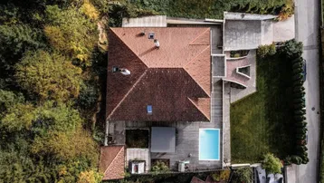 Luftaufnahme des Anwesens mit Satteldach, Poolbereich, Garten und angrenzendem Wald.