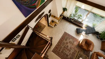 Geräumiges Wohnzimmer mit hoher Decke, Wendeltreppe und Kamin, von oben fotografiert.