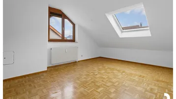 Helles Zimmer im Dachgeschoss mit Parkettboden, Dachfenster und Bergblick.