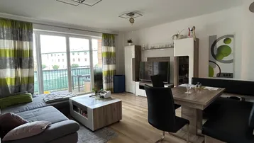 Helles Wohn- und Esszimmer mit modernem Laminatboden und Zugang zum Balkon.