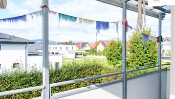 Überdachter Balkon mit weitem Blick über die Dächer und grüne Umgebung.