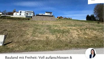 Unbebautes Hanggrundstück mit Blick auf moderne Häuser und grüne Umgebung unter blauem Himmel.