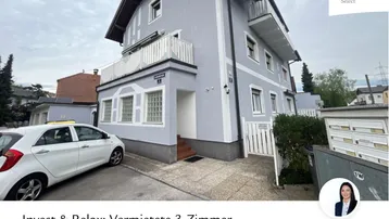 Mehrfamilienhaus mit hellgrauer Fassade, Balkonen und einem geparkten Auto davor.