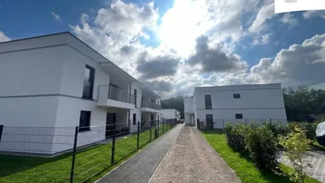 Moderne Wohngebäude mit weißer Fassade und Balkonen unter blauem Himmel.