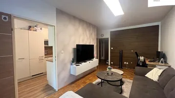 Gemütliches Wohnzimmer mit modernem TV-Möbel, Holzakzenten und Zugang zur Küche.