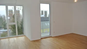 Heller Raum mit Parkettboden, großen Fenstern und Zugang zu einem Außenbereich, bietet viel natürliches Licht.