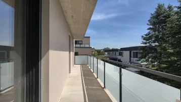 Langer Balkon mit Glasbrüstung und Blick auf die Umgebung, ideal für sonnige Tage.